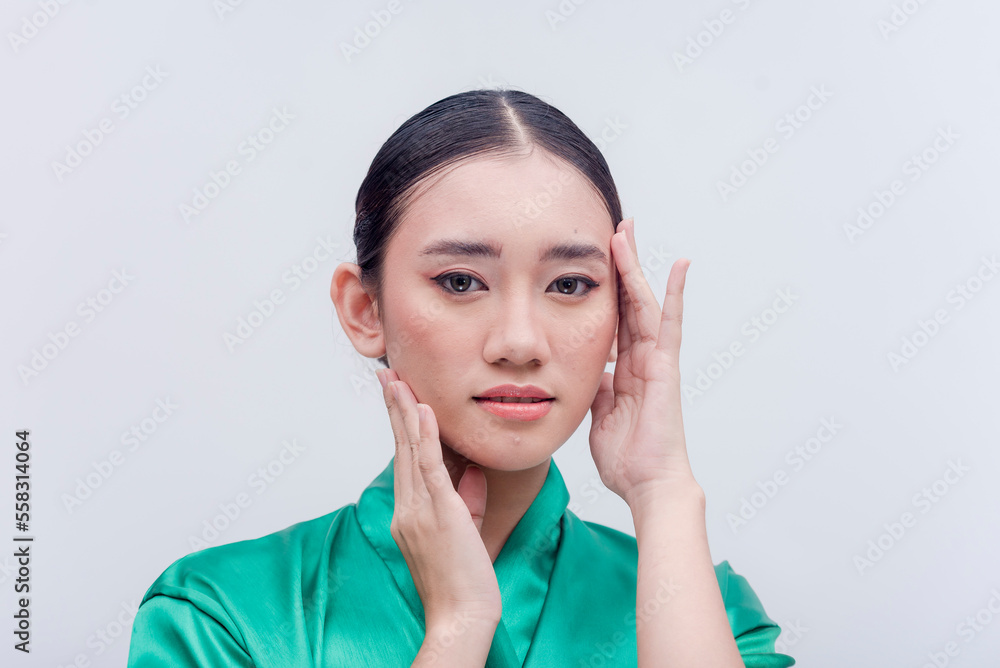 Southeast Asian female executing the popular migraine selfie hand pose for a studio photo shoot isolated on a white background. Young woman putting her hands on her smooth face. Iconic headache pose. Southeast Asian female executing the popular migraine selfie hand pose for a studio photo shoot isolated on a white background. Young woman putting her hands on her smooth face. Iconic headache pose.