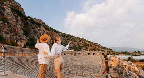 Happy lover couple tourist archaeologist in hat background old tomb Myra Ancient City in Demre to Antalya, archaeology of Turkey