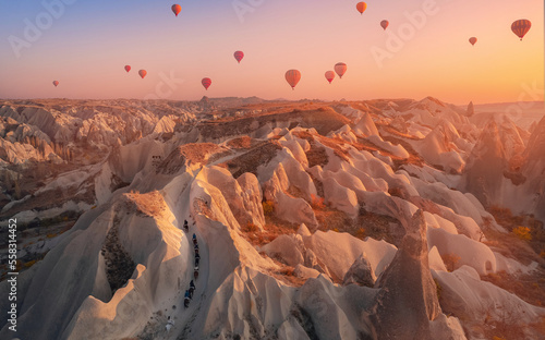 Horse tourist tour on rose valley of Cappadocia Turkey, national park Goreme with hot air balloons. Aerial top view landscape sunset
