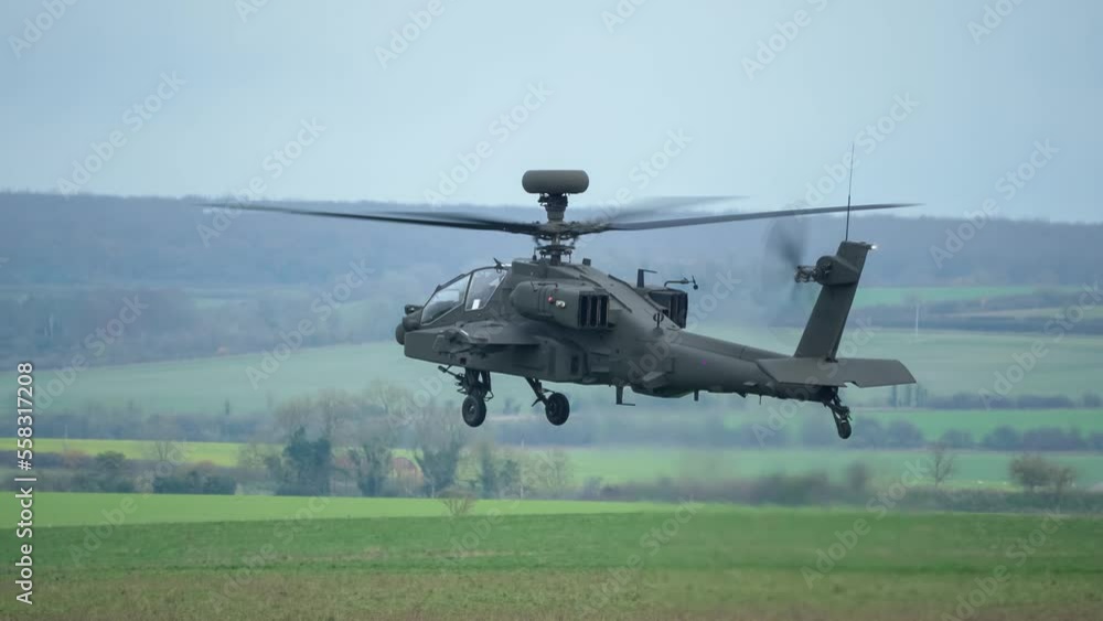 British army Boeing Apache Attack helicopter gunship (AH-64E AH64E) hovers and rotates just above a grass meadow, Wiltshire UK British army Boeing Apache Attack helicopter gunship (AH-64E AH64E) hovers and rotates just above a grass meadow, Wiltshire UK