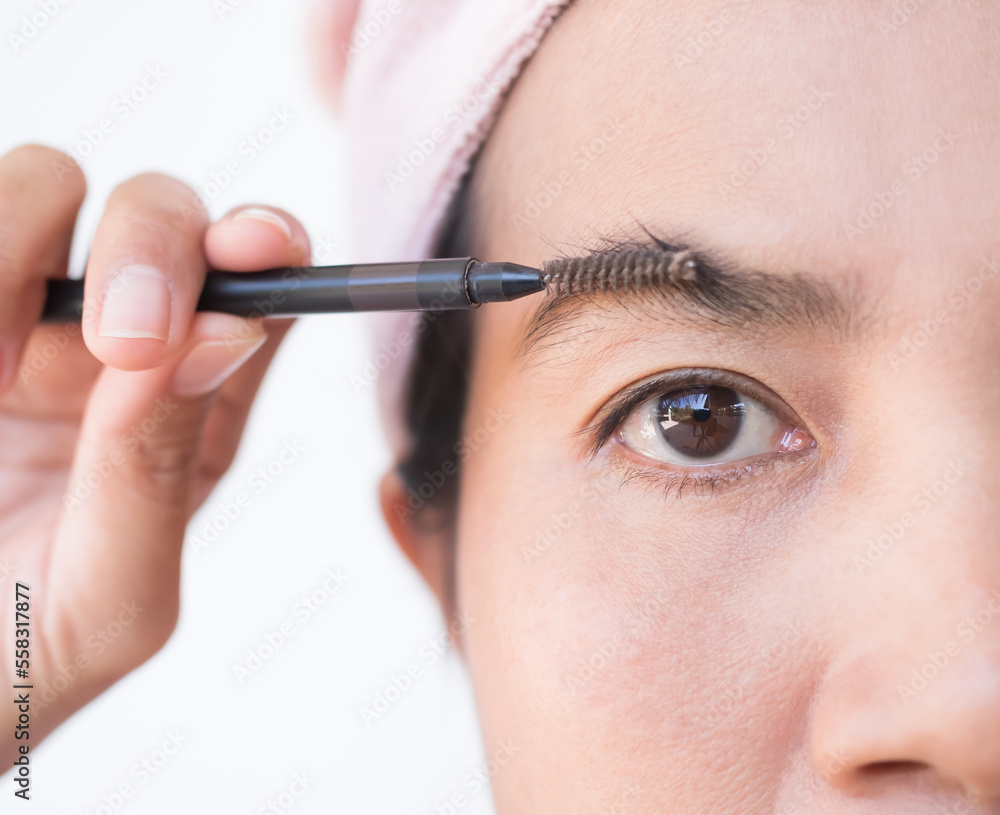 Woman Draw eyebrows Eyebrow Brush Close up,Girl Shaping brows Brushing Eyebrows,Portrait Makeup Face Beauty Cosmetic,Authentic Skin Tan and Black Eyes Asian Thailand.