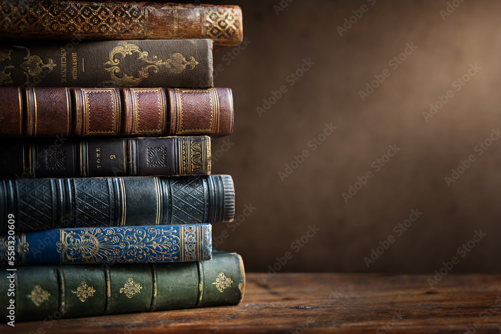 Old books on wooden desk and ray of light. Bookshelf history theme