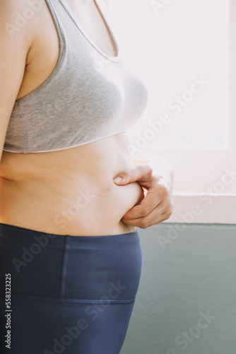 Beautiful fat woman with tape measure She uses her hand to squeeze the excess fat that is isolated on a white background. She wants to lose weight, the concept of surgery and break down fat under the