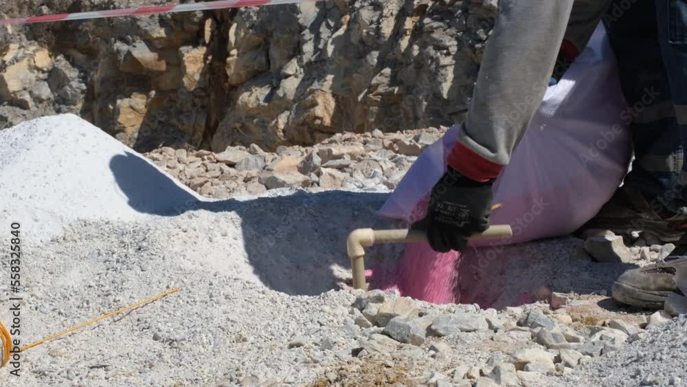 Pouring explosives into dug holes for quarry explosion. Explosive dust dumping into the excavated hole. Pouring explosives into dug holes for quarry explosion. Explosive dust dumping into the excavated hole.