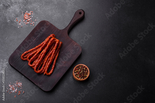 Delicious thin smoked meat sausages with spices and herbs photo