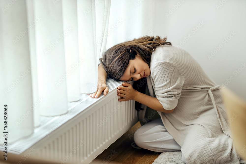 A pregnant woman is hugging warm radiator. A pregnant woman is hugging warm radiator.