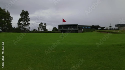 red golf pole flag on manicured green at golf course hole 18 by club house photo