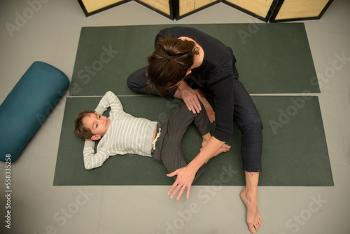 Caucasian osteopath performing stretches with a young boy