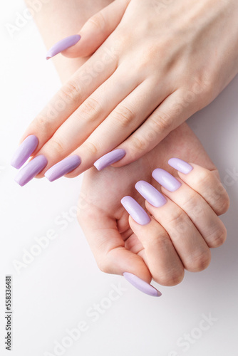 Hands of a girl with a soft purple manicure on a white background.