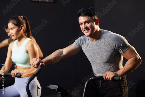 young athletic man cycling exercise bikes at the gym