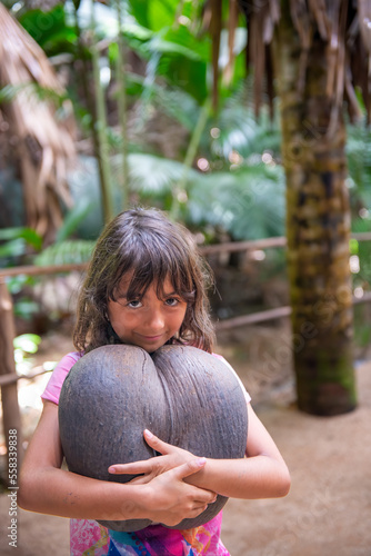 Young girl embracing Coco De Mer along a beautiful tropical trail, Vallee de Mai photo