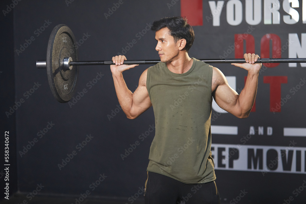 young athletic man exercising with barbell in the gym
