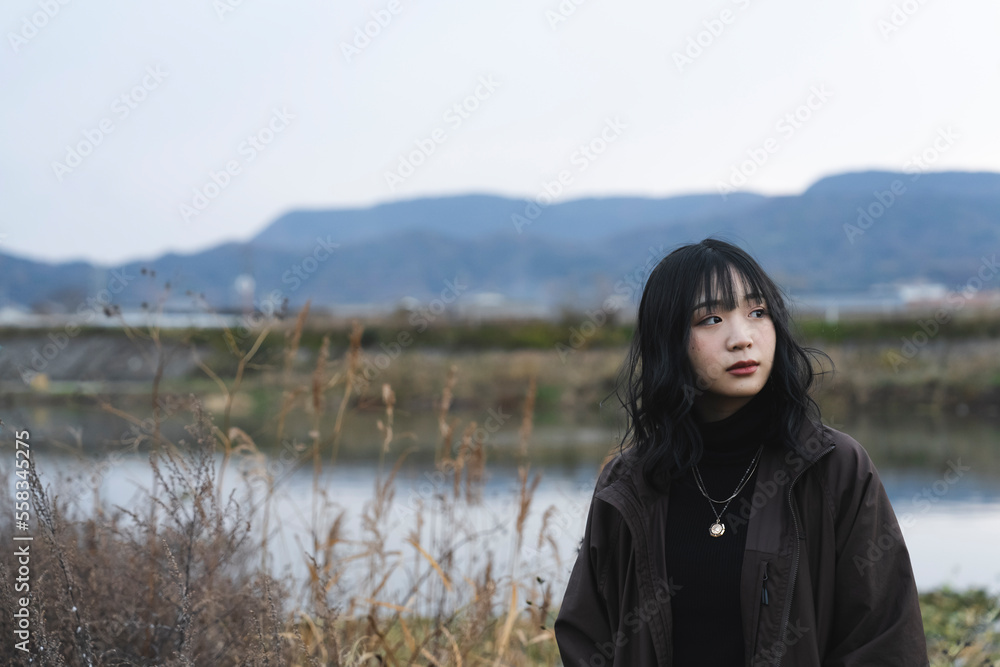 冬の河川敷に立つ女性 冬の河川敷に立つ女性