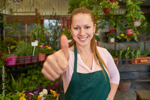 Stolze Floristin mit Daumen nach oben im Blumenladen photo