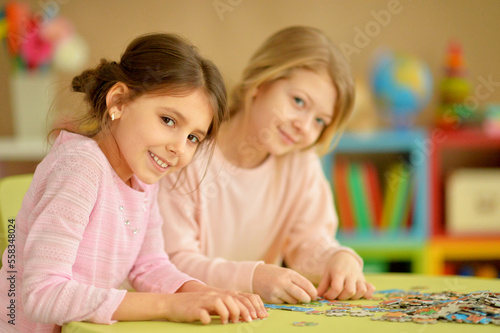 little girls collecting puzzle pieces while sitting at table