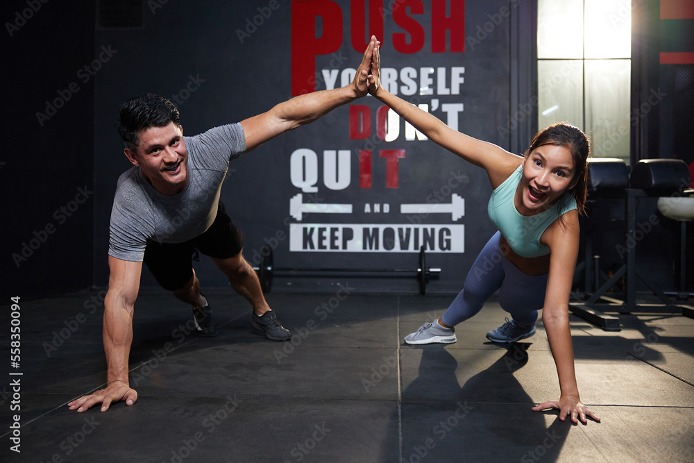 athletes in sportswear doing push up and hi five pose in the gym