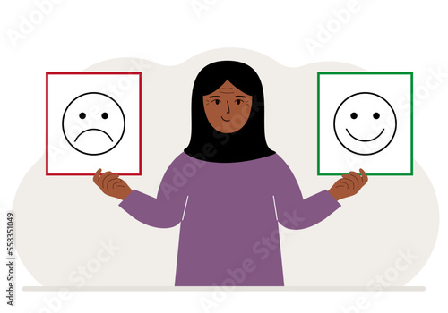 Smiling woman holds a card with a sad emoji in one hand and a smiling emoji in the other hand. The concept of emotions, masks or psychological help.