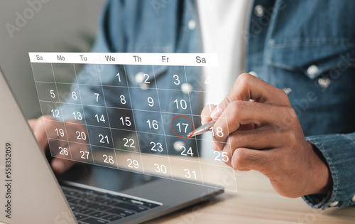 Businessman manages time for effective work. Calendar on the virtual screen interface. Highlight appointment reminders and meeting agenda on the calendar. Time management concept. photo