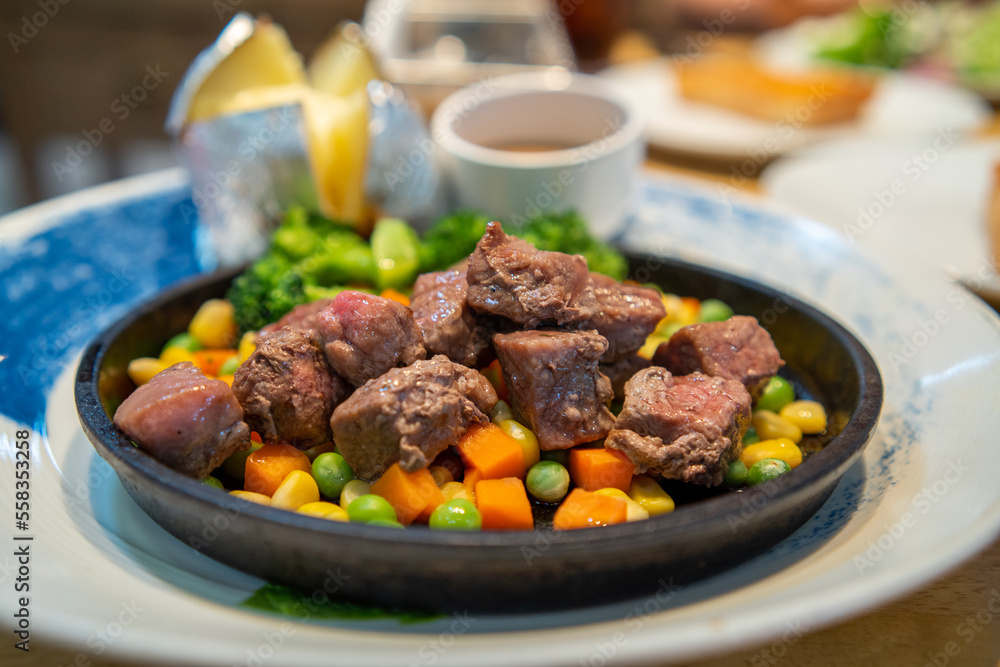 Beef Cubes Steak with mixed vegetables on a sizzler plate