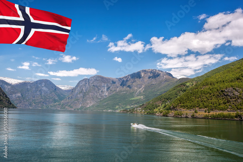 Port of Flam with tourist boat in the fjord with flag of Norway
