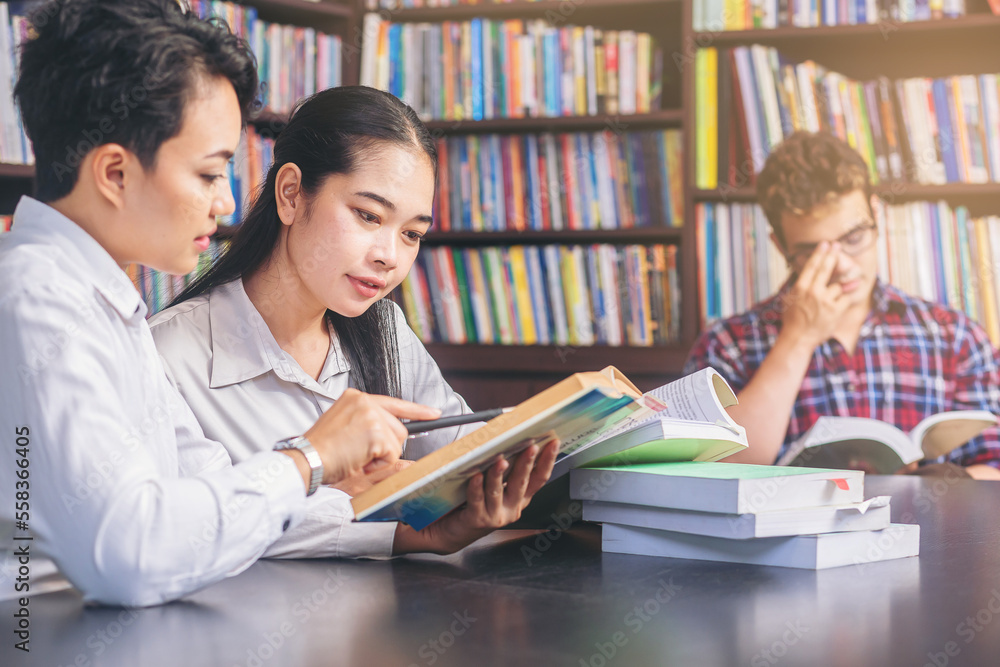 Asian college students sitting reading, studying, examining, Tutor books with friends. People learning education concept Asian college students sitting reading, studying, examining, Tutor books with friends. People learning education concept