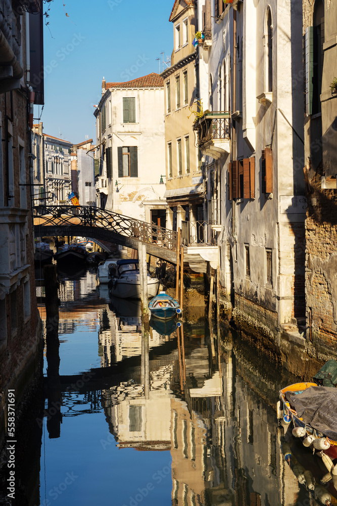 Fototapeta premium Boats covered from rain parked in the water next to the house in canal of Venice. Water transport and transportation theme. Morning in Venice.