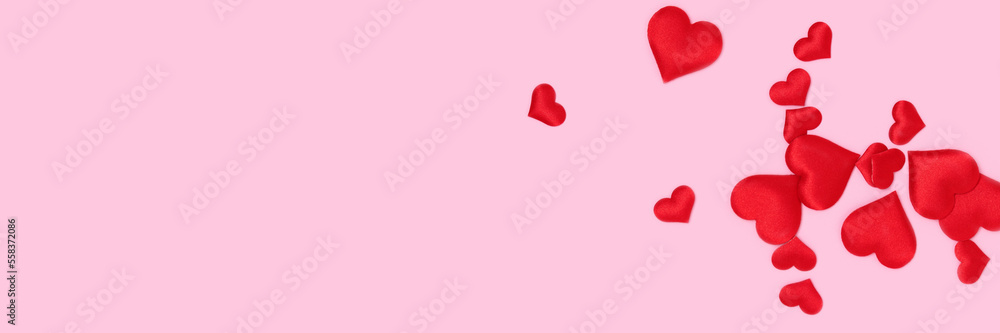 Banner with red textile hearts confetti scattered on a pink background. Place for text.