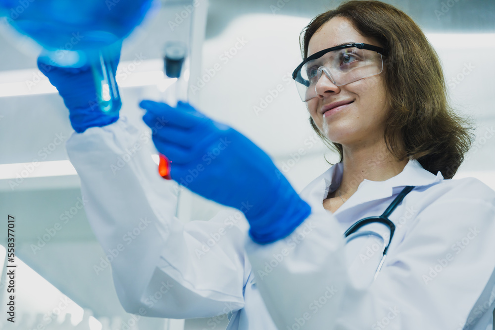 Scientist examining plant in test tube in lab Scientist examining plant in test tube in lab