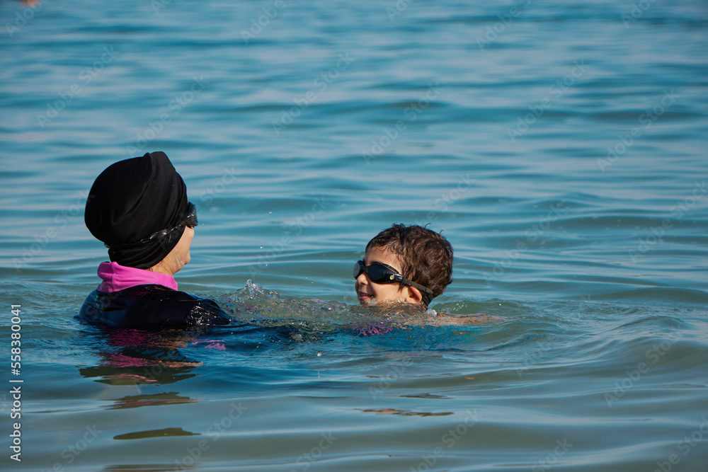 Mother teaching her son how to swim at the sea. child playing with his mother at sea