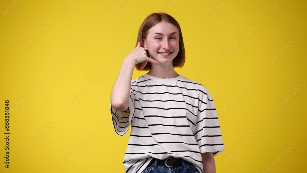 4k slow motion video of girl making telephone gesture near head call me sign on yellow background. 4k slow motion video of girl making telephone gesture near head call me sign on yellow background.