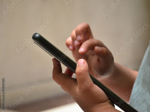 Manos de un niño tocando un teléfono celular. Pequeño jugando con la tecnología 