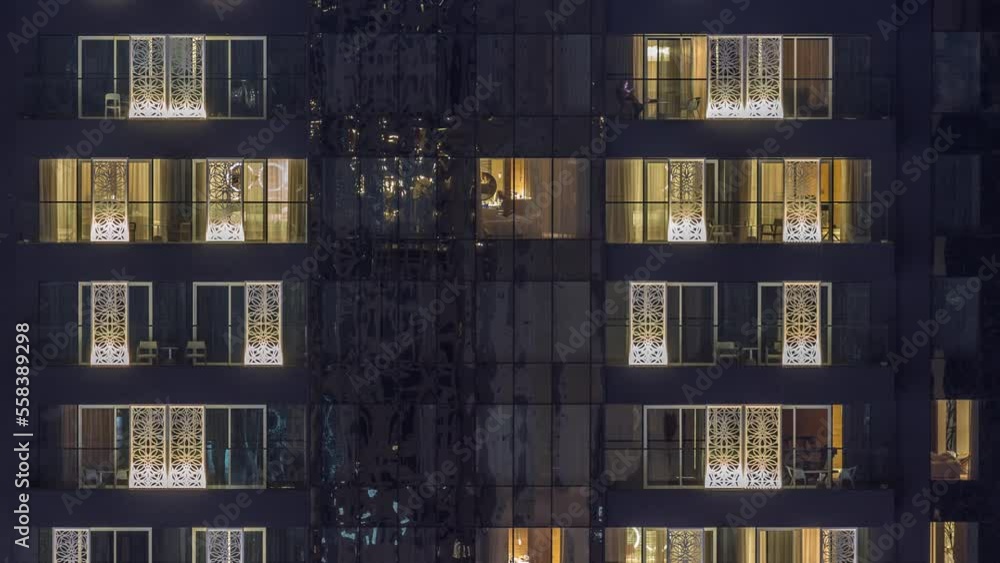 Windows lights in modern office and residential buildings timelapse at night. Multi-level skyscrapers with illuminated rooms inside. Some chairs on balconies Windows lights in modern office and residential buildings timelapse at night. Multi-level skyscrapers with illuminated rooms inside. Some chairs on balconies