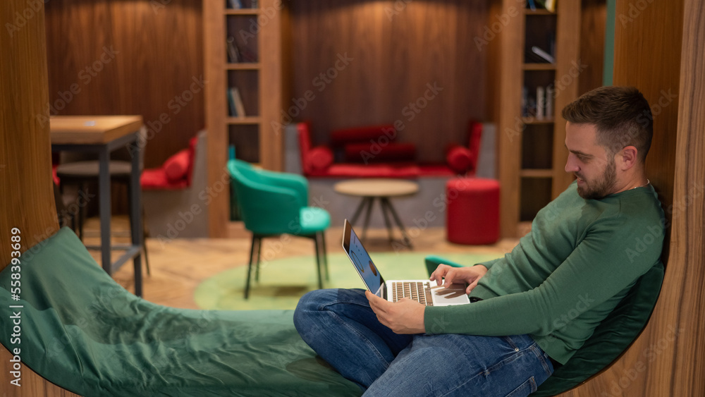 Caucasian bearded man working on laptop in modern coworking. Caucasian bearded man working on laptop in modern coworking.