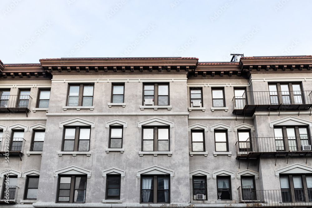 Face of an old urban apartment building with classic details, window lentils and sills, roof overhang mouldings, horizontal aspect