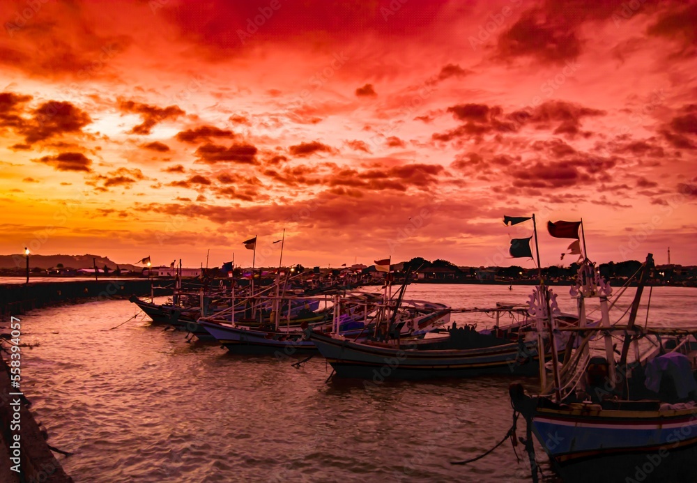sunset over the harbor, the evening sky and the silhouettes of several fishing boats on the pier 