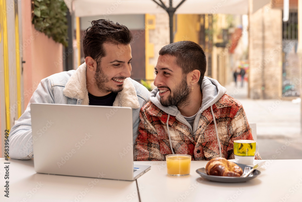 smiling gay couple at cafe using laptop smiling gay couple at cafe using laptop