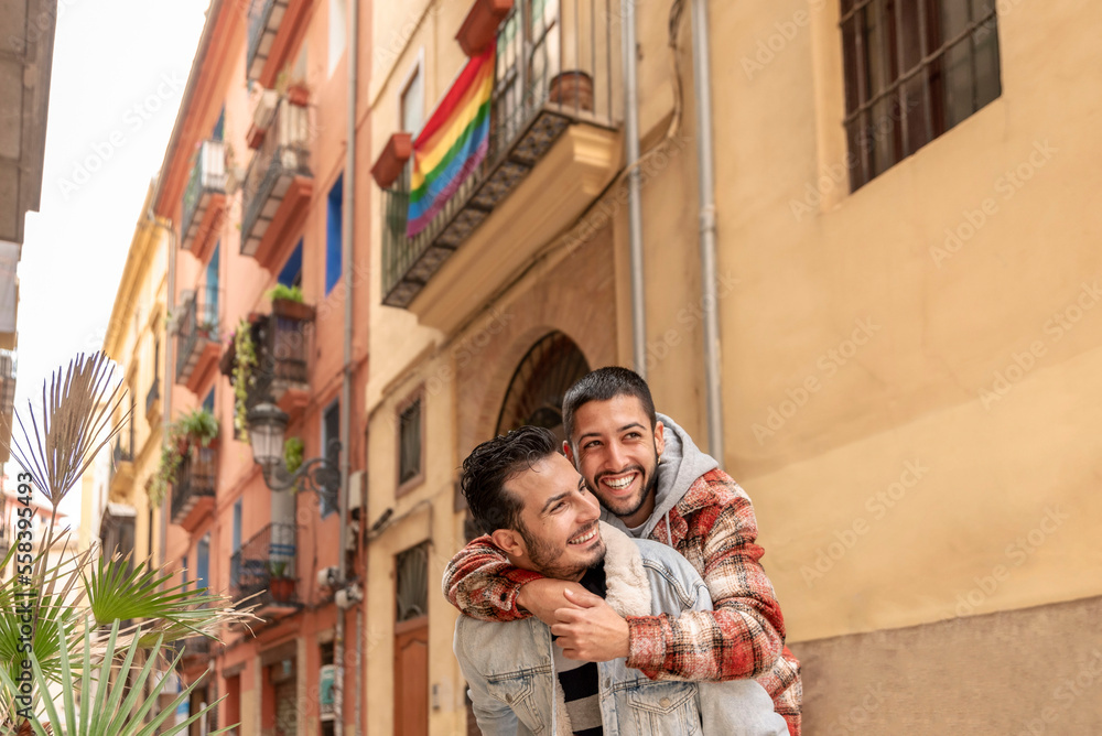 gay couple having fun, flag of pride in the background