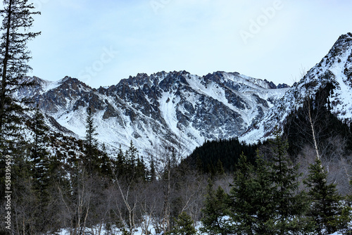 Snow-covered mountain, morning fog, mountain rocky ridges with pointed peaks, winter, sunny, Kyrgyzstan, Ala Archa photo