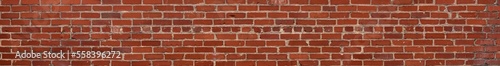Extremely long thin panorama of red brick wall with irregular bricks in running bond pattern, horizontal aspect