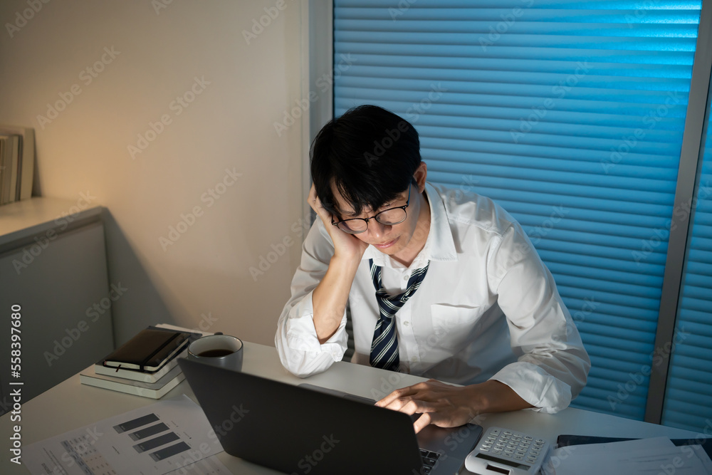 Tired Asian business man falling asleep at table Alone Working Late at Night.on laptop computer at night in dark office. works in the later time Tired Asian business man falling asleep at table Alone Working Late at Night.on laptop computer at night in dark office. works in the later time