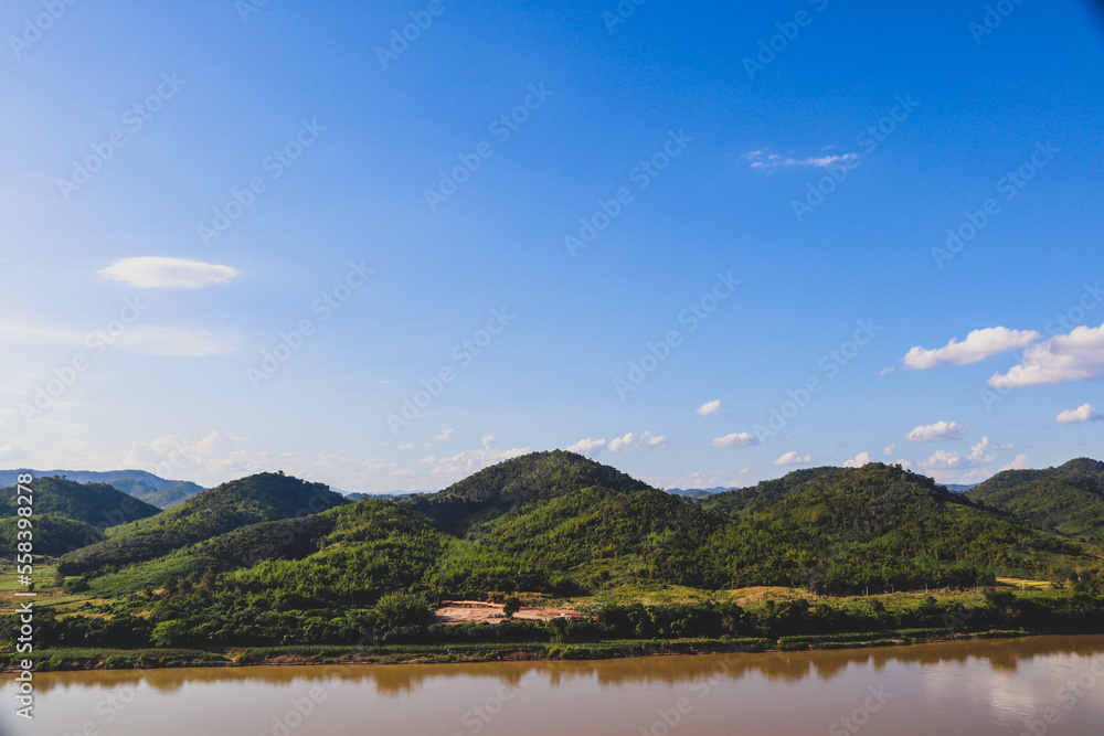 Beautiful natural scenery of river in tropical green forest with trees on two sides and mountain in background
