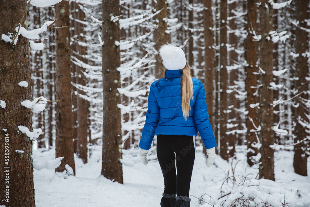 Hiker female enjoying the first snow in the forest. The concept of winter leisure and active recreation, walks in the woods.
