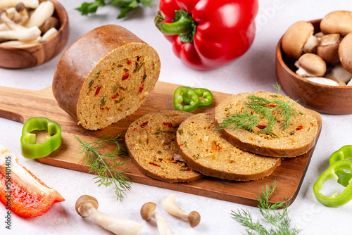 Mushroom based vegan sausage with vegetables and spices on wooden board, top view