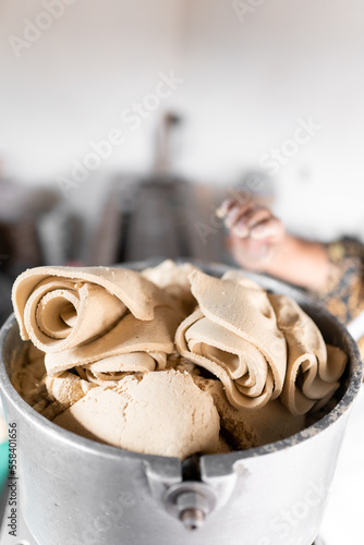 An adult tortilla maker is dropping some corn dough into the nixtamall mill in Mexico. Close up photo