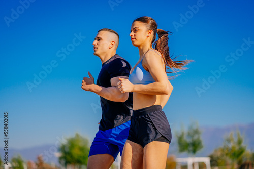 A side view photo of two friends running together