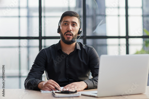 Positive businessman talking on headset at a computer