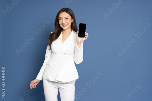 Portrait of Asian business woman showing or presenting mobile phone application isolated over blue background, Asia Thai model