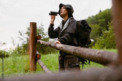 Young african woman tourist using binoculars during hiking in countryside