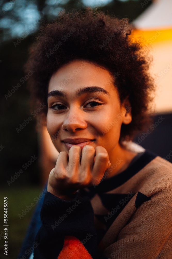 Young african woman smiling at camera while sitting outdoors Young african woman smiling at camera while sitting outdoors