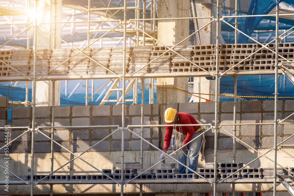 Man working on construction site with scaffold and building with sun set background,scaffolding for construction factory